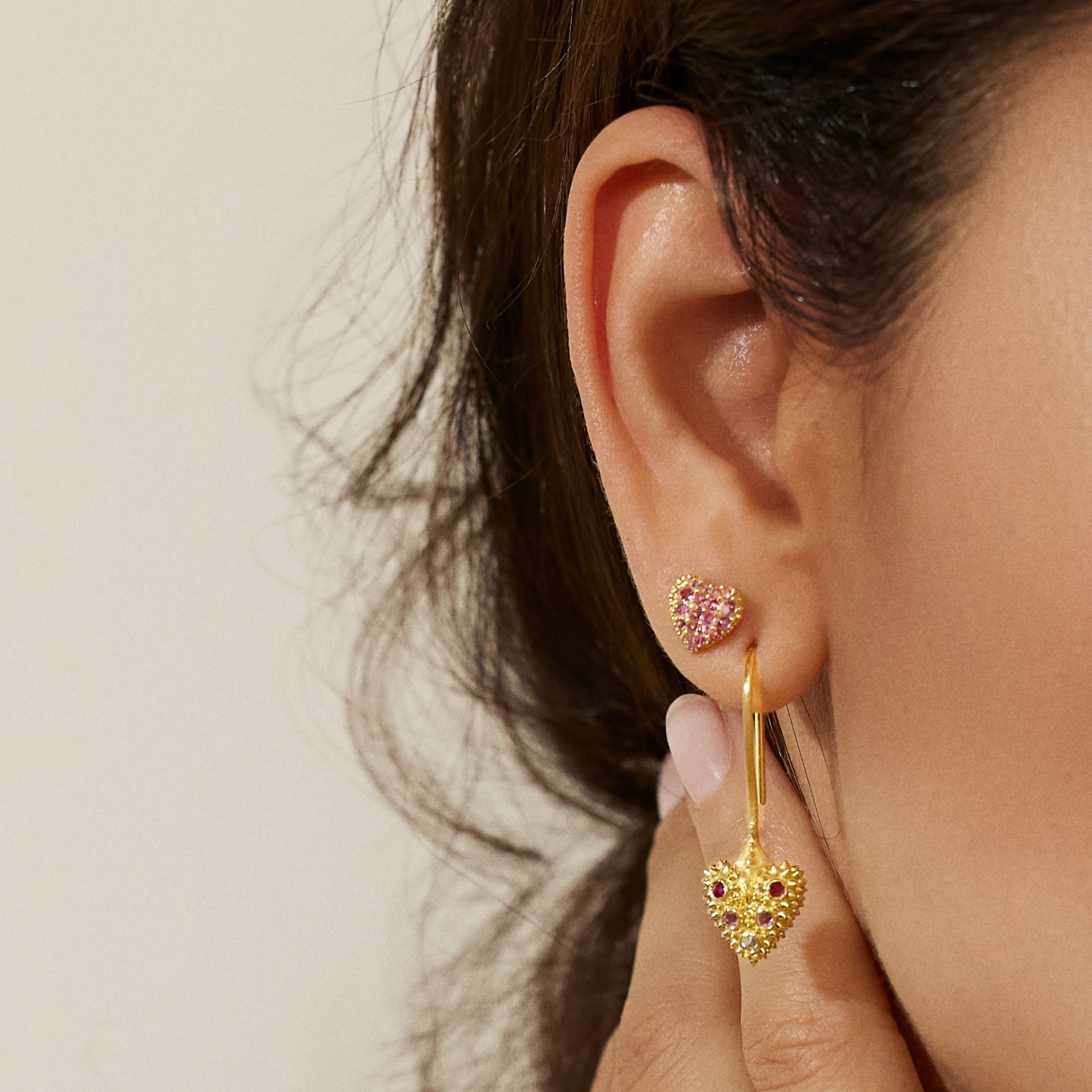 A model wearing 18k yellow gold heart-shaped stud & drop earrings with soft spikes - designed by Ana-Katarina fine jewelry as well as other unique jewelry from AK’s ‘Pierce Your Heart’ collection.