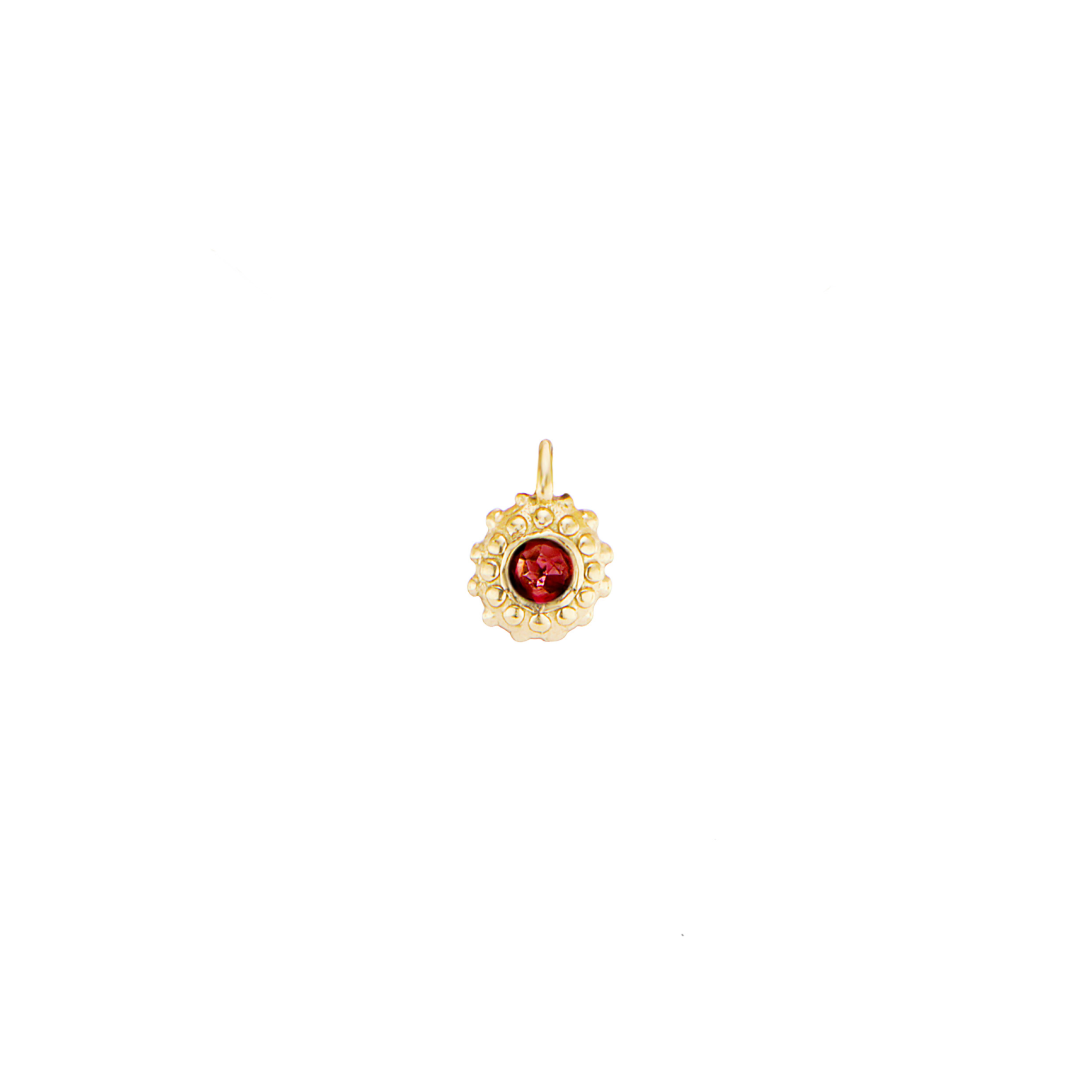 An 18k yellow gold circular charm with raised soft 'spikes' and an inverted garnet for the January / Capricorn birthstone in the center.