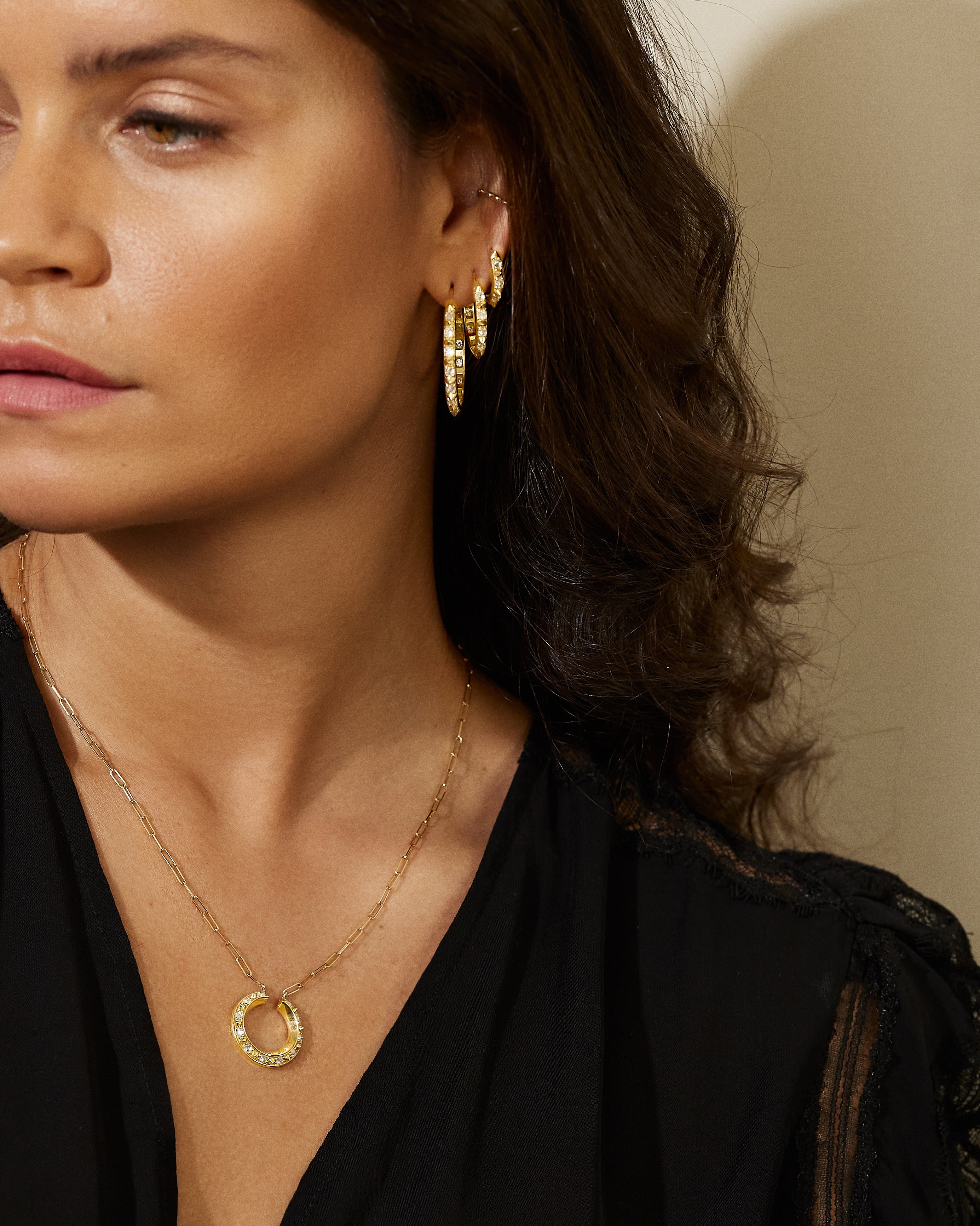 A model wearing the opulent Large Valerie Diamond Hoops in white and yellow, crafted with 18k yellow gold and adorned with inverted diamonds and gold spikes, they're a reinvented classic gold hoop earring.