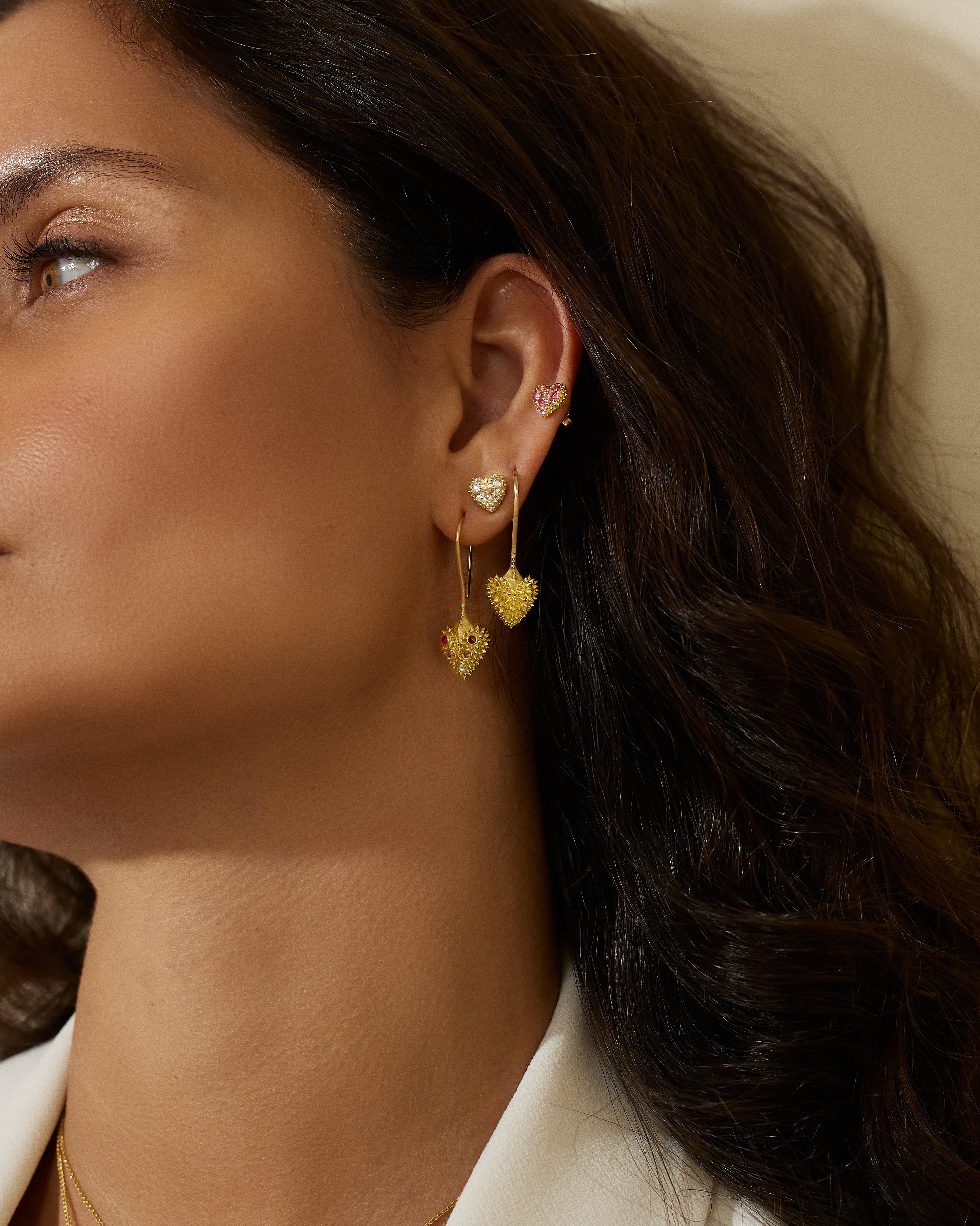 A model wearing 18k yellow gold drop heart earrings with soft spikes - designed by Ana-Katarina fine jewelry as well as other unique jewelry from AK’s ‘Pierce Your Heart’ collection.