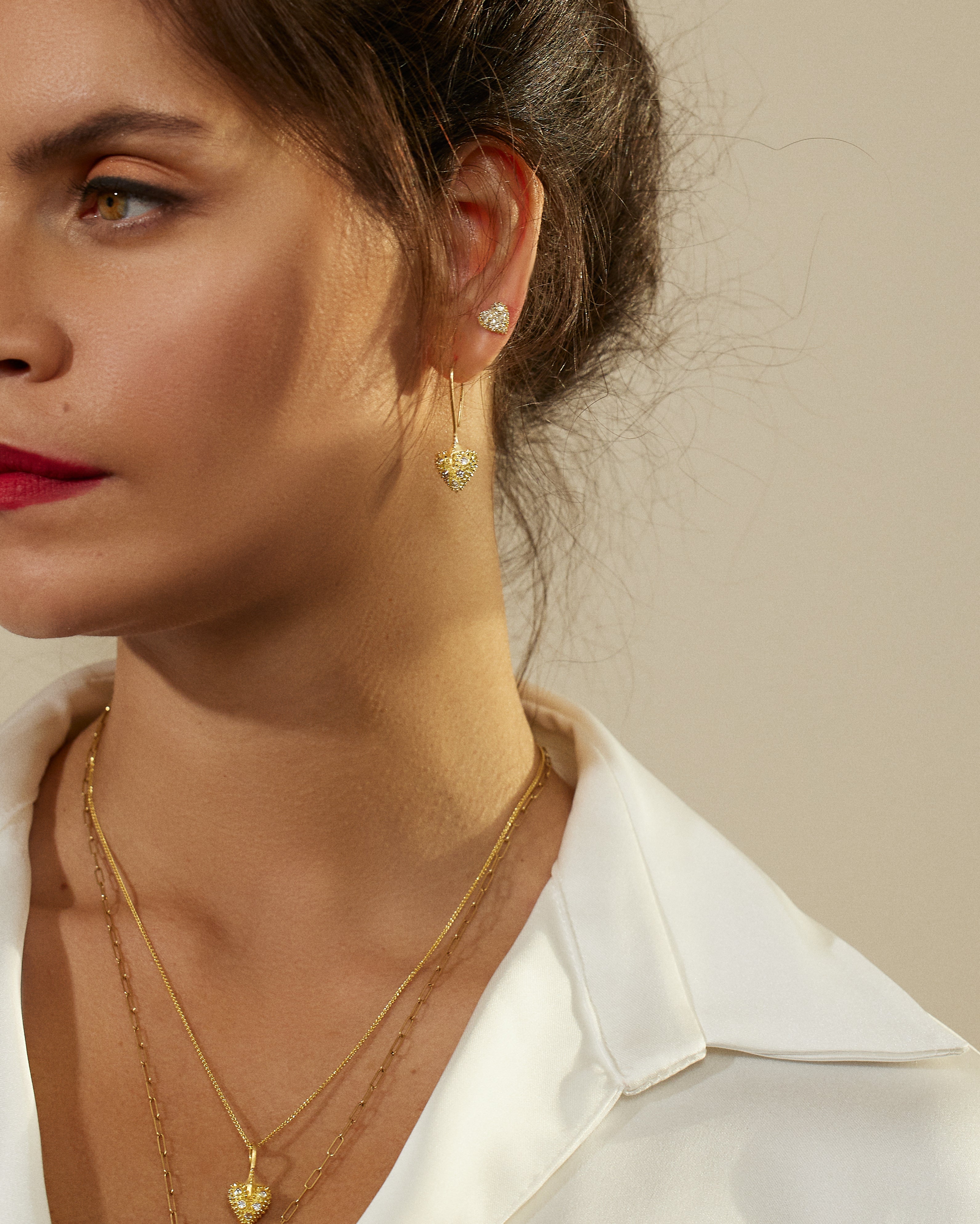 A model wearing 18k yellow gold drop heart earrings with soft spikes - designed by Ana-Katarina fine jewelry as well as other unique necklaces & stud earrings from AK’s ‘Pierce Your Heart’ collection.