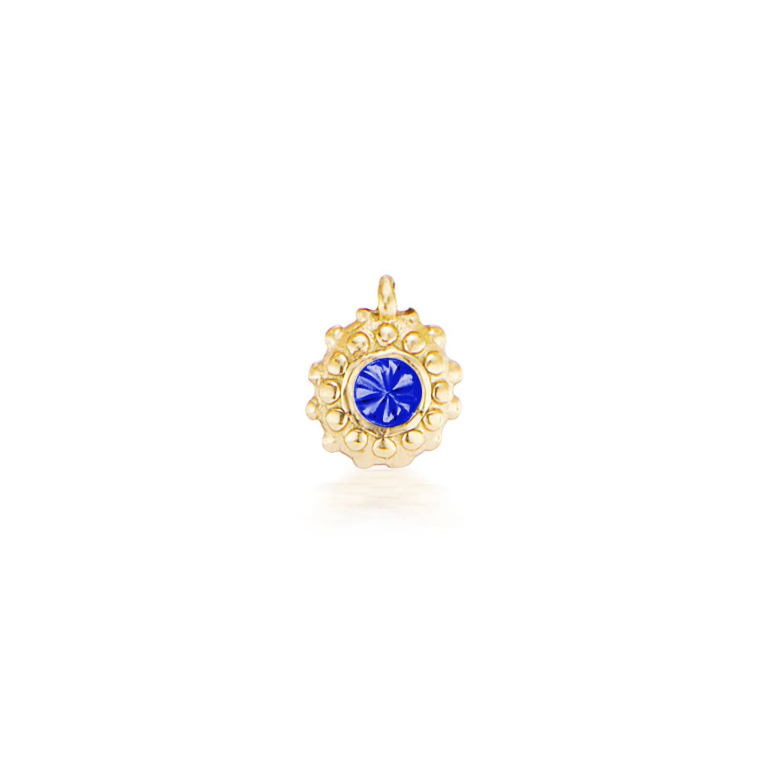 An 18k yellow gold circular charm with raised soft 'spikes' and an inverted tanzanite for the December / Sagittarius birthstone in the center.