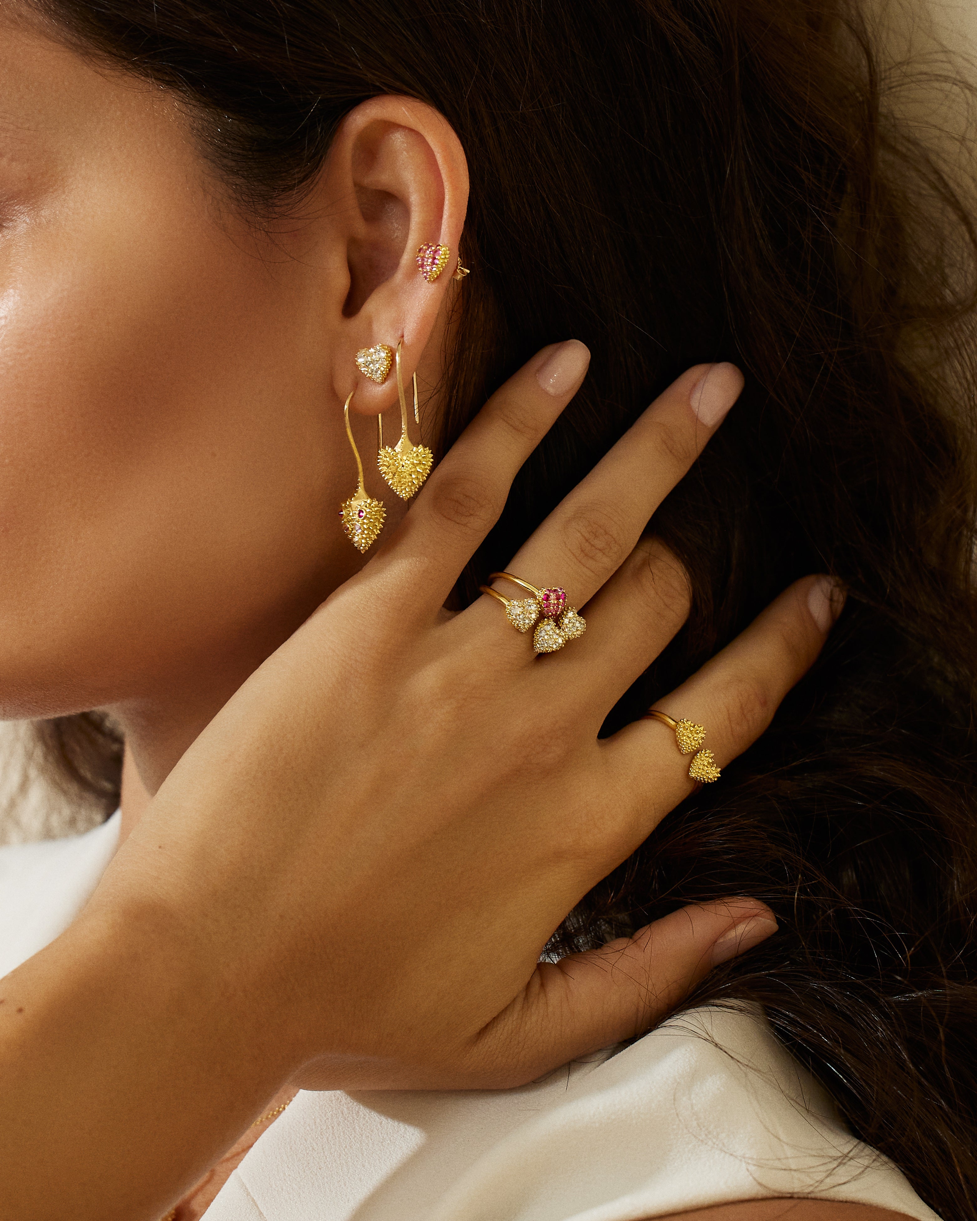 A model wearing 18k yellow gold drop heart earrings with soft spikes - designed by Ana-Katarina fine jewelry as well as other unique rings & stud earrings from AK’s ‘Pierce Your Heart’ collection. 