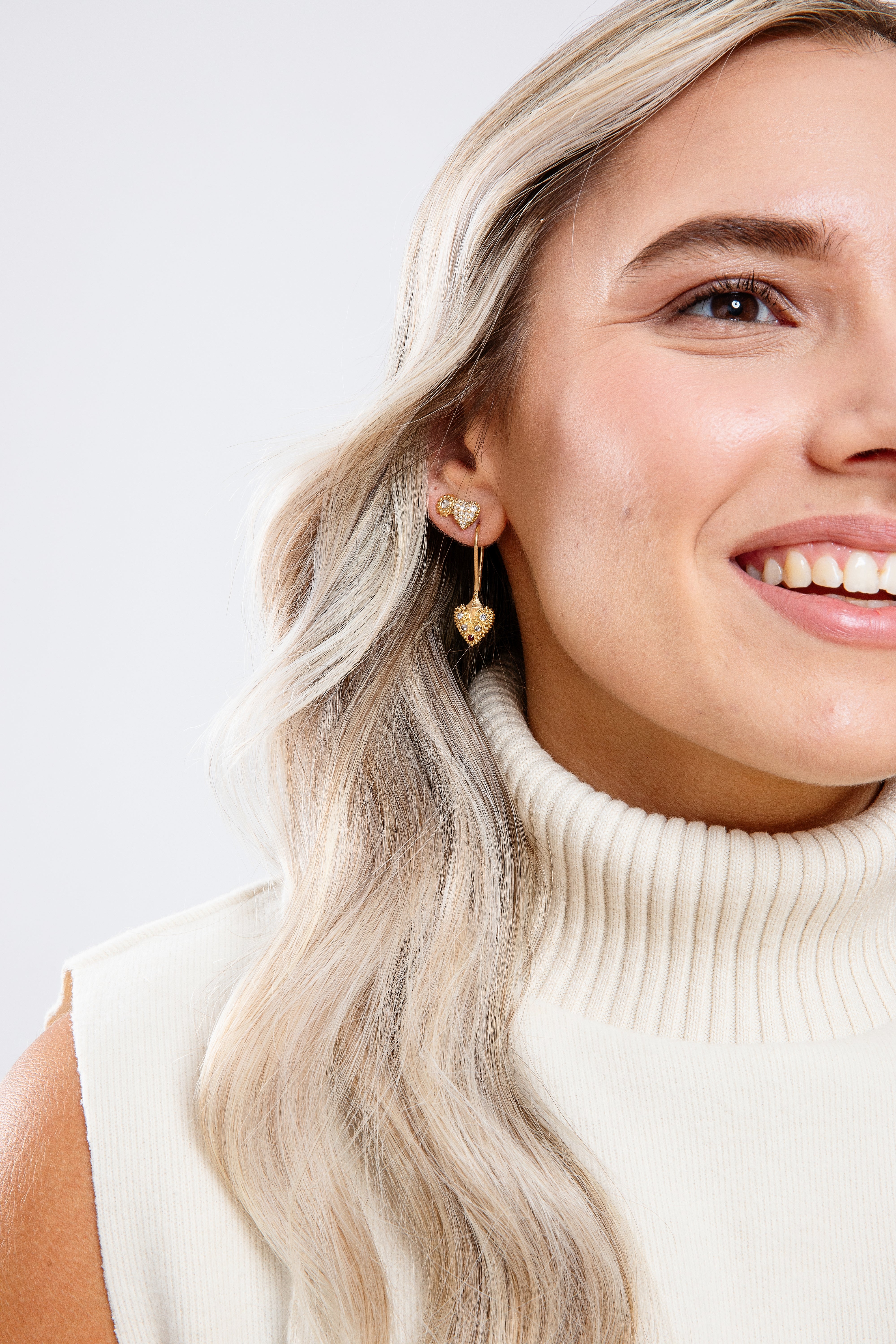 A model wearing various 18k yellow gold and diamond drop and stud earrings designed by Ana-Katarina Fine Jewelry. 