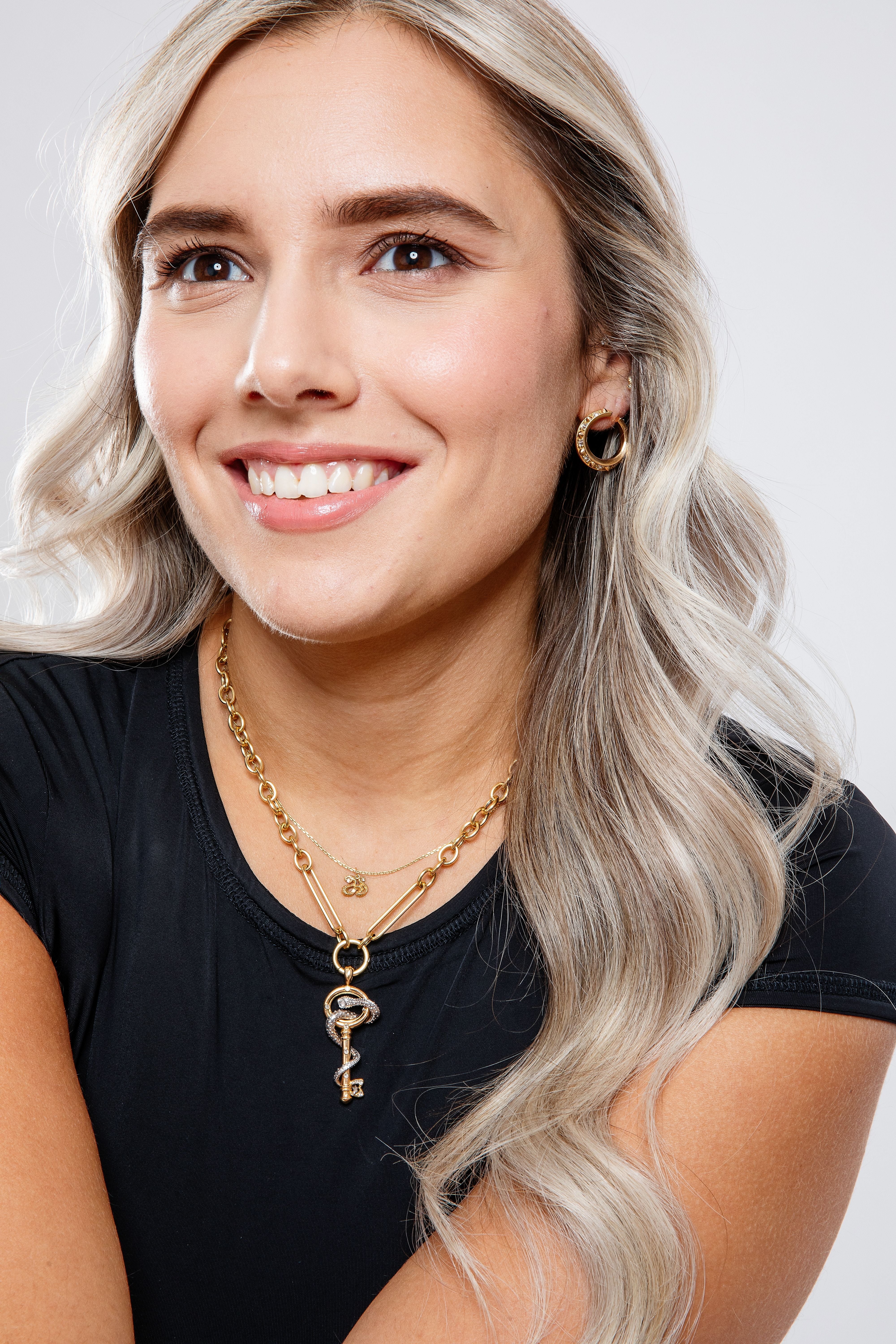 A model wearing a black top to highlight the 18k gold serpent key pendant styled on the 18” ‘Olivia’ yellow gold chain. 