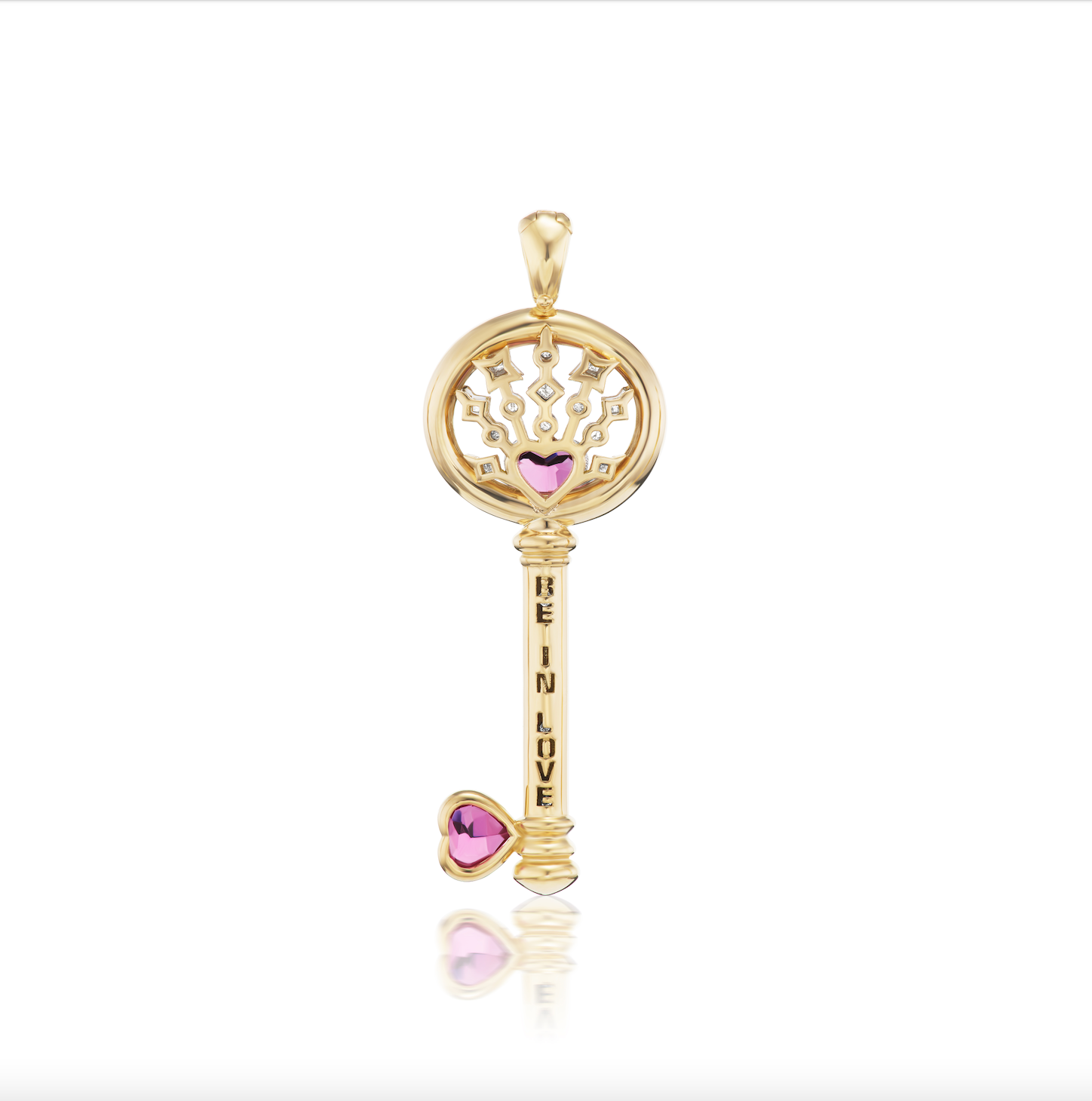 The reverse side of AK's Impeccable Words: 'Love' Key Pendant in 18k yellow gold with two pink tourmaline hearts & diamonds with the words “Be In Love” tooled into the gold stem of the key shown against a white background. 