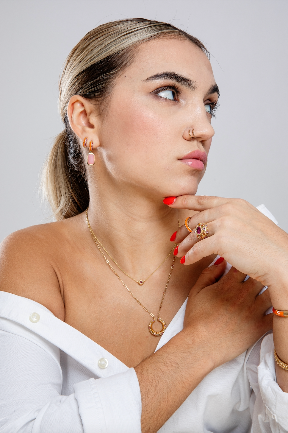 A person wearing fine jewelry in pink and orange from the Attitude 'Sweet Little Life' 18k yellow gold & pink tourmaline collection with orange enamel accents. Designed by Ana-Katarina Fine Jewelry.