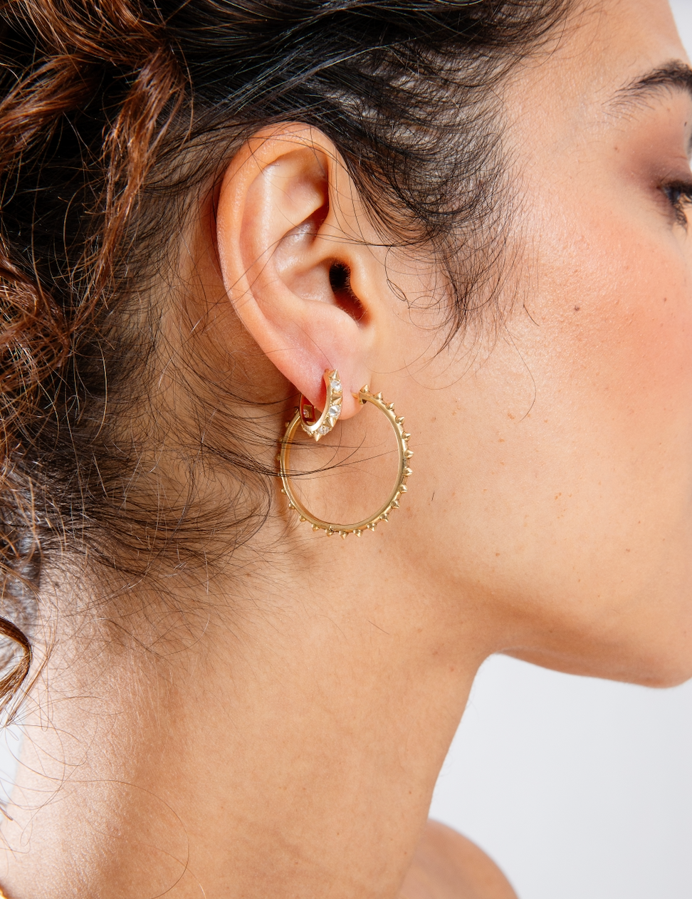 A person with dark hair modeling Ana-Katarina's 'Adrina Loves a Hoop' 18k gold large hoop earrings & the Valerie Diamond Mini Hoops -both from the Attitude Collection. Designed by Ana-Katarina Fine Jewelry. 