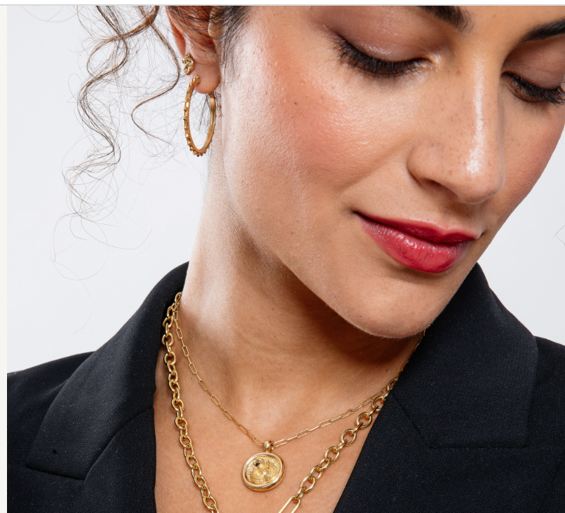 A person with dark hair modeling Ana-Katarina's 'Adrina Loves a Hoop' 18k gold large hoop earrings along with necklaces, chains & earrings from Ana-Katarina's fine jewelry collections. Designed by Ana-Katarina Fine Jewelry. 