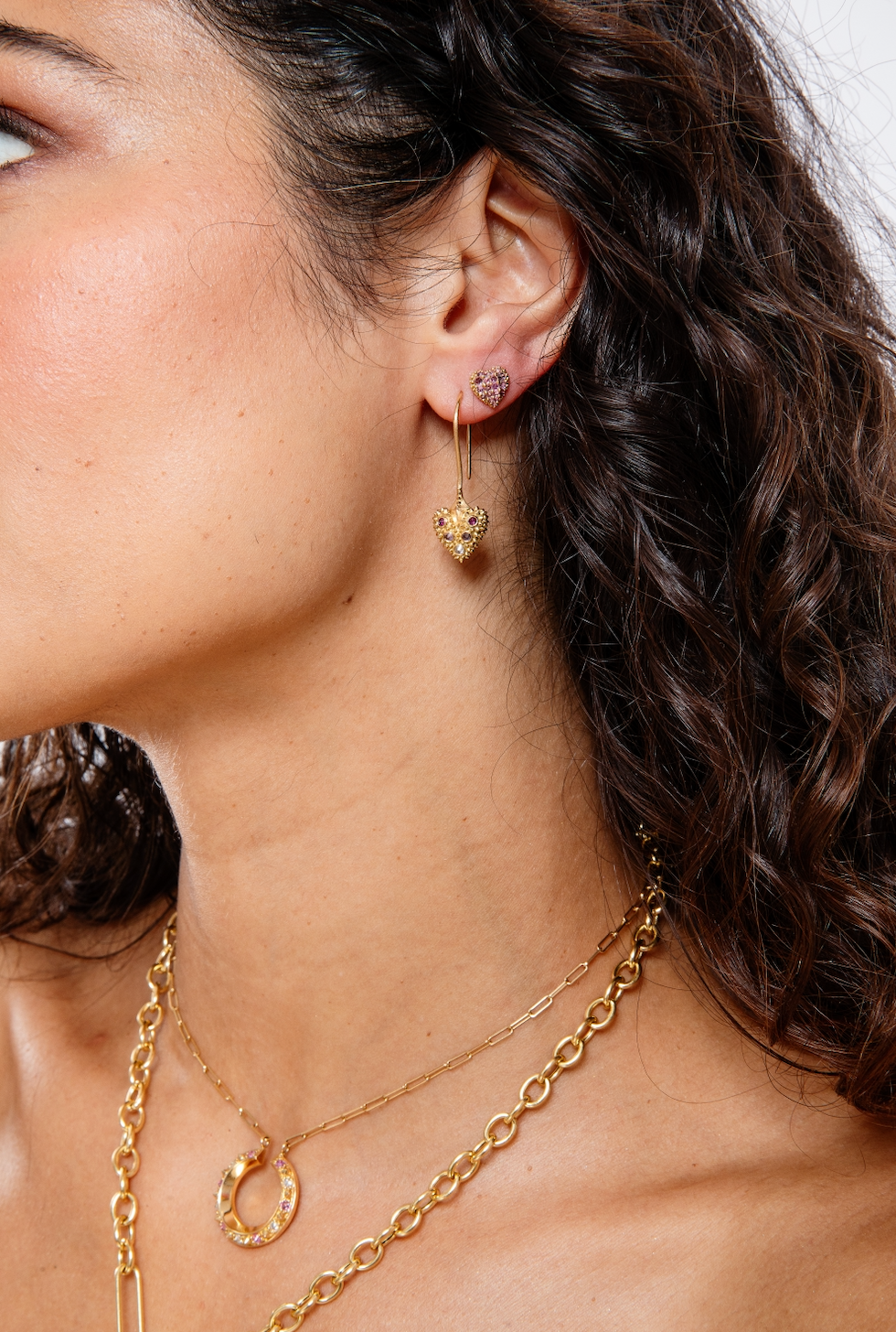 A model wearing 18k yellow gold drop and stud earrings with inverted pink sapphires and soft gold spikes from Ana-Katarina’s ‘Pierce Your Heart’ collection. 