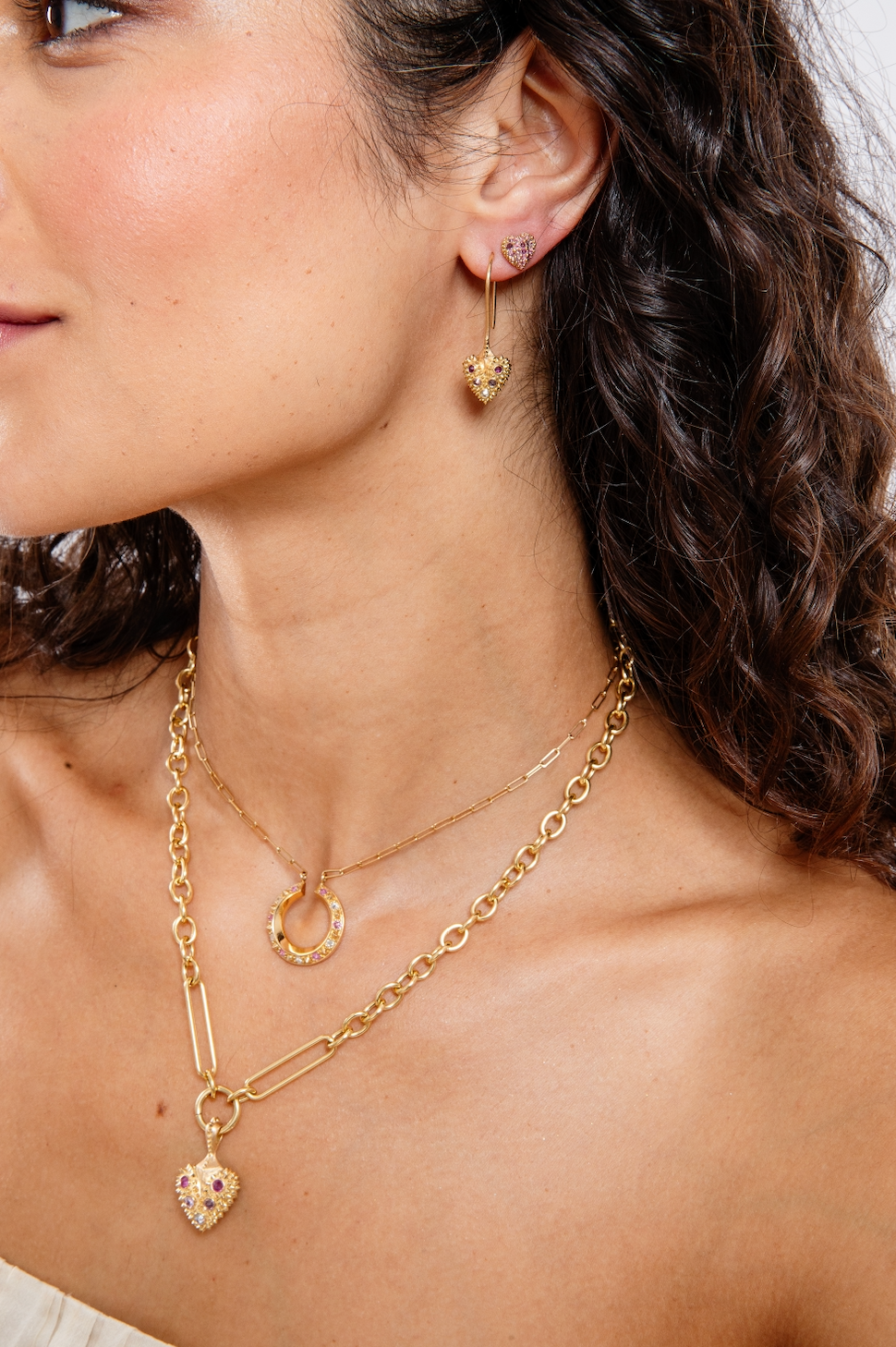 A model wearing an 18k gold heart with inverted pink sapphires & diamond with 18k yellow gold spikes on an 18k yellow gold Olivia chain - designed by Ana-Katarina fine jewelry.