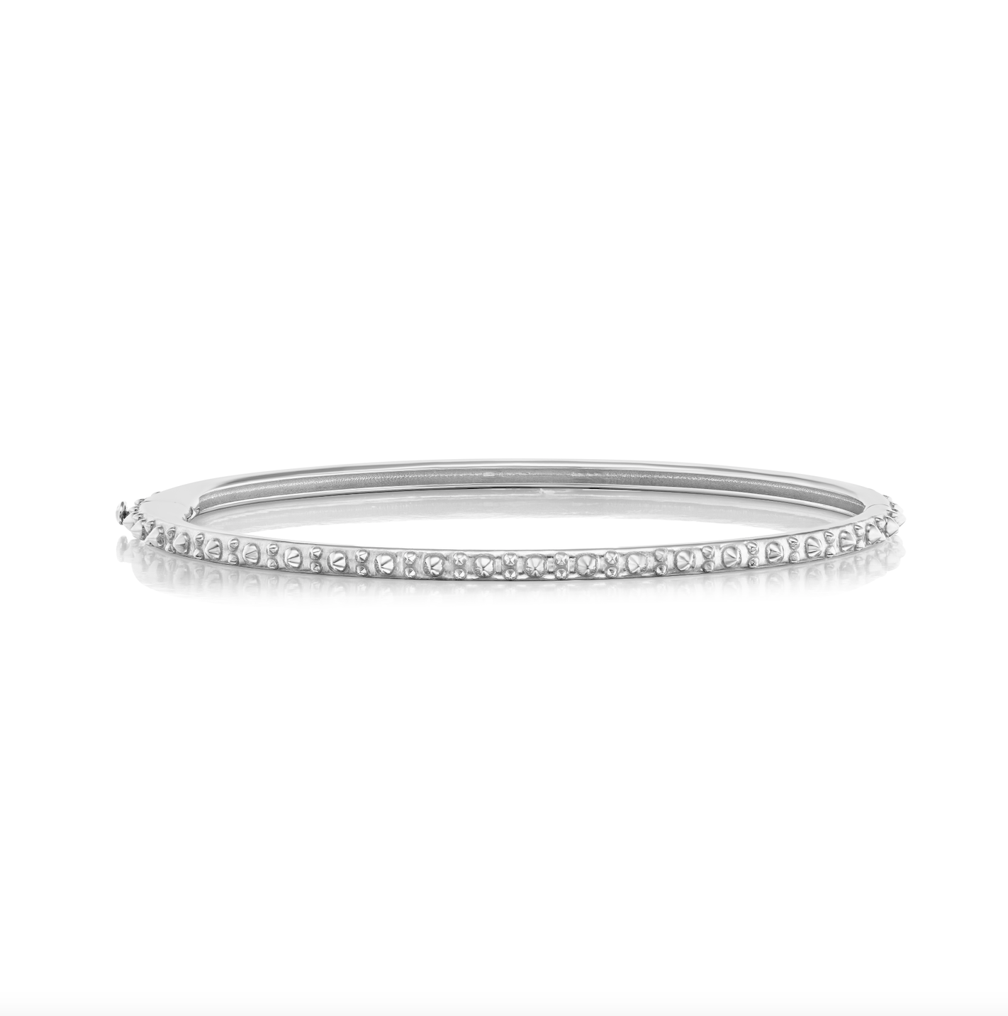 A straight on view of AnaKatarina's Attitude White Gold 'Adrina Loves a Bangle' 18 karat white gold bangle. In her reinvention of the classic bangle, AK combines traditional form with a fusion of confidence and femininity, showcasing 18k gold spikes. 