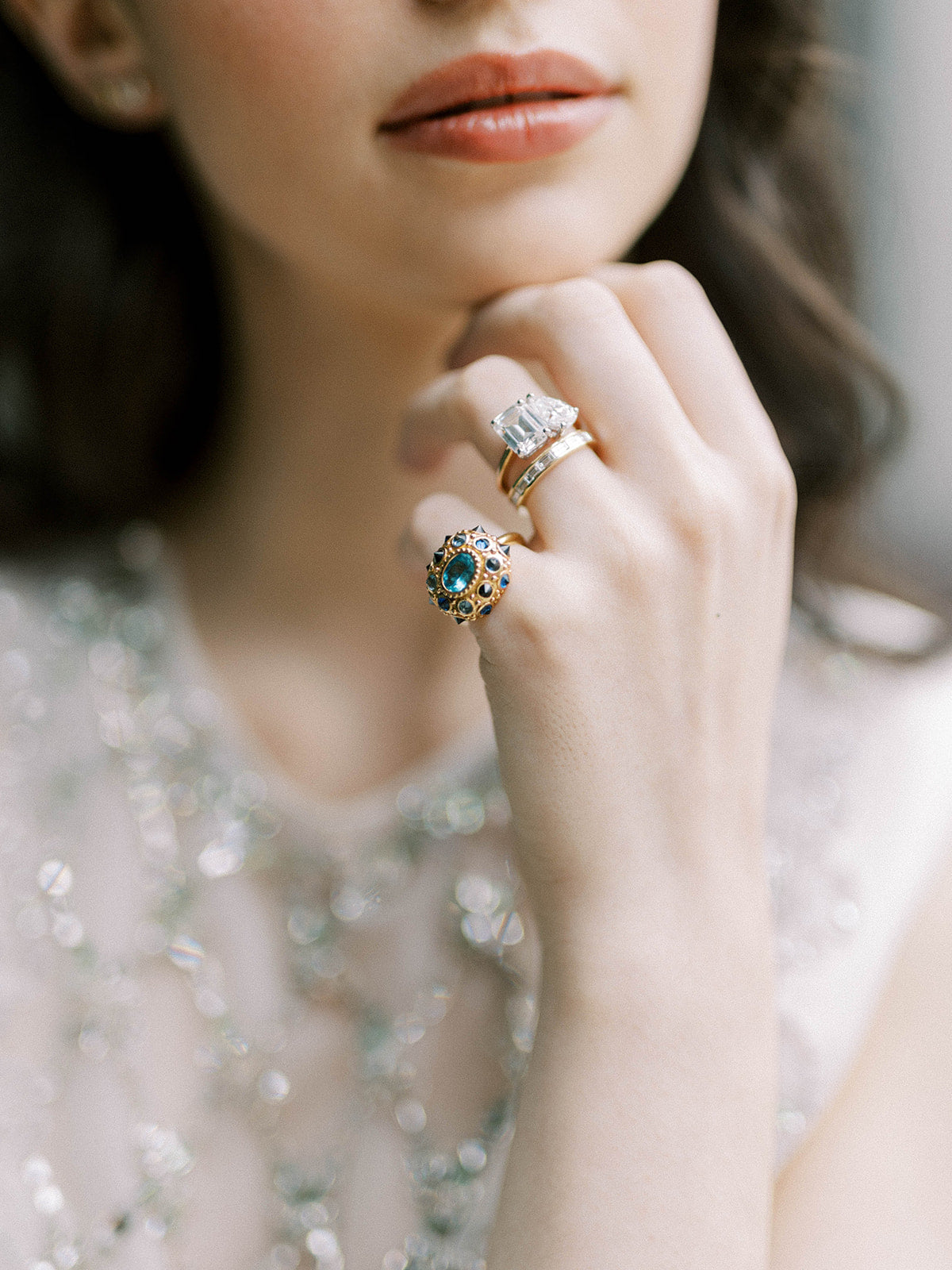 A model showcasing this stunning 'A Twinkle in Twilight Ring' crafted in 18K yellow gold by AnaKatarina for her 'Attitude' line, adorned with Apatite, Blue Sapphires, and Black Diamonds, featuring an exquisite design inspired by the sea urchin.