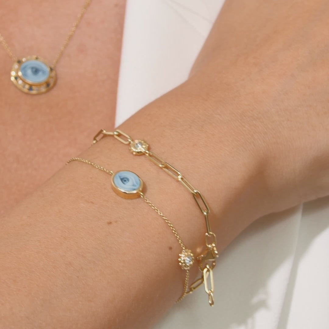 A video of a person modeling Ana-Katarina's ‘Eye Love’ Charm Bracelet in 18k yellow gold, blue agate, and inverted diamonds alongside other fine jewelry from Ana-Katarina Fine Jewelry. 