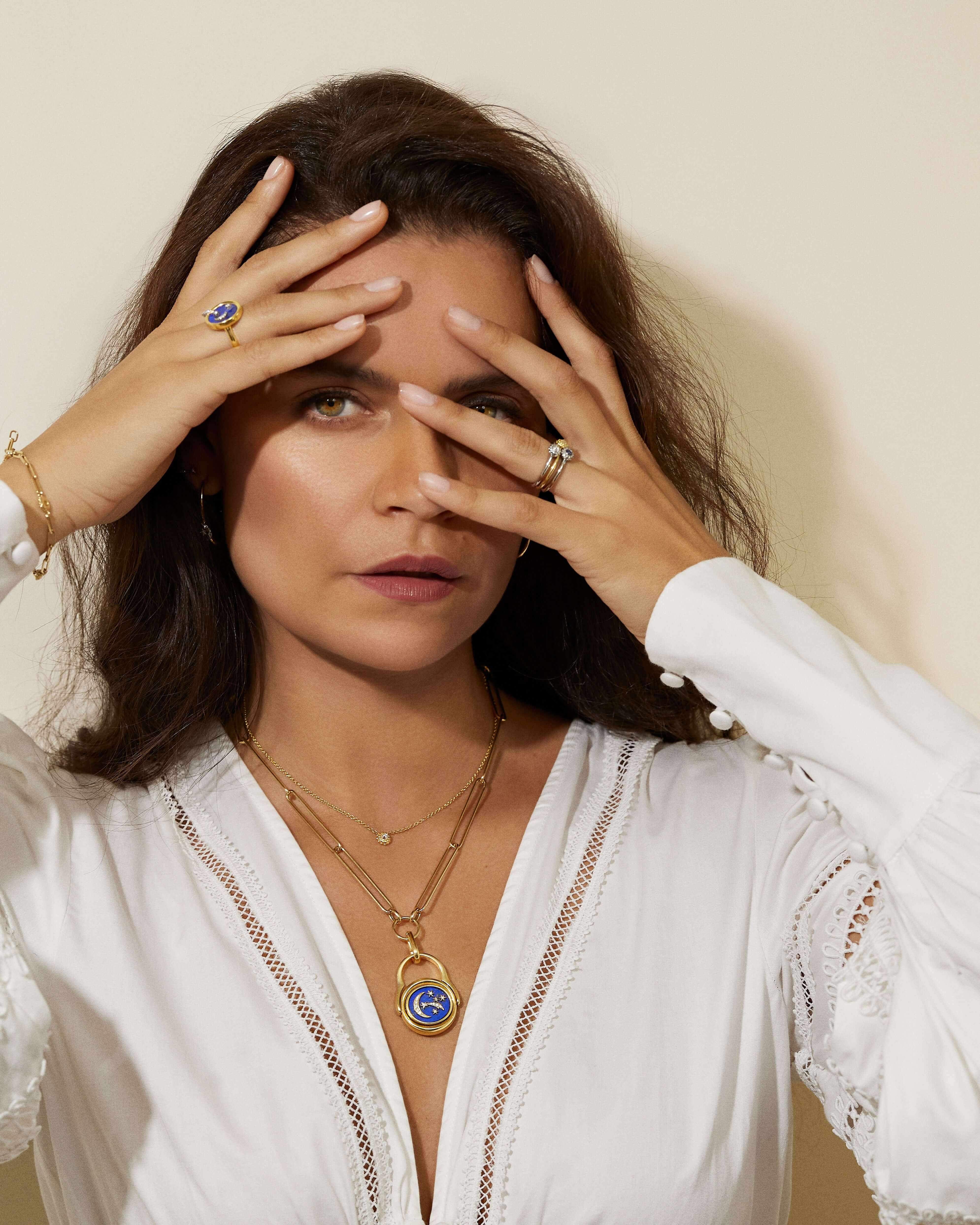 A person modeling Ana-Katarina's 4 Elements Air Flip Ring as a pendant in 18k gold, diamonds, and blue enamel featuring the moon and shooting stars.