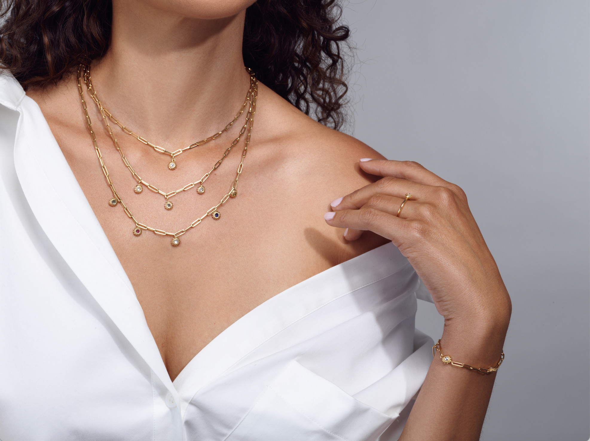 A model wearing various necklaces, rings, and bracelets from the ‘California Dreaming’ and ‘Tribe’ collections by Ana-Katarina Fine Jewelry. All pendants, rings, and bracelets are in 18k yellow gold in a sea-urchin-inspired design with soft gold beading - all with 18’ adjustable paperclip chains.