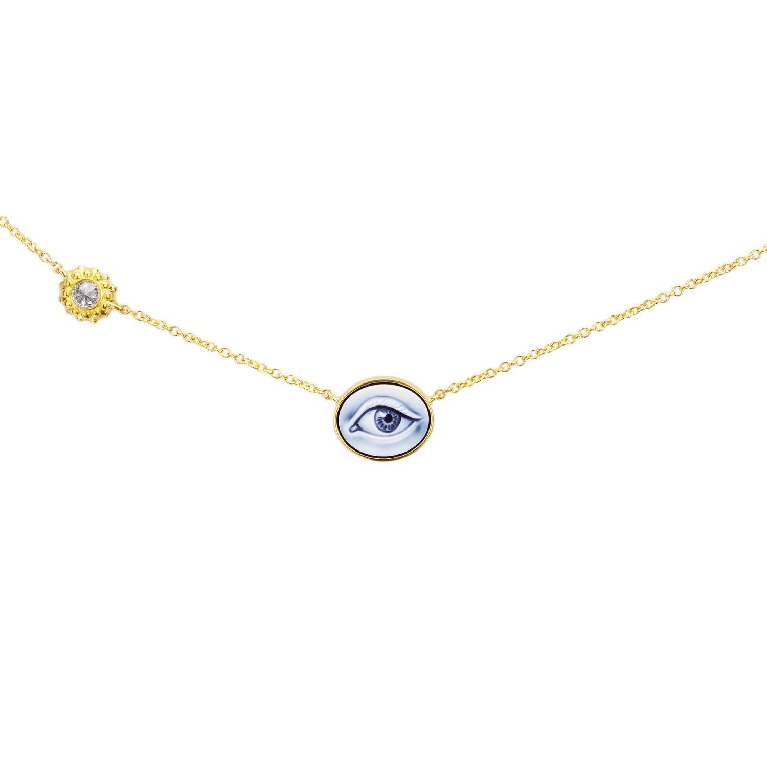 An 18k yellow gold necklace with a blue agate cameo into which a human eye is hand-carved alongside an 18k yellow gold setting with an inverted diamond. Designed by Ana-Katarina Fine Jewelry. 