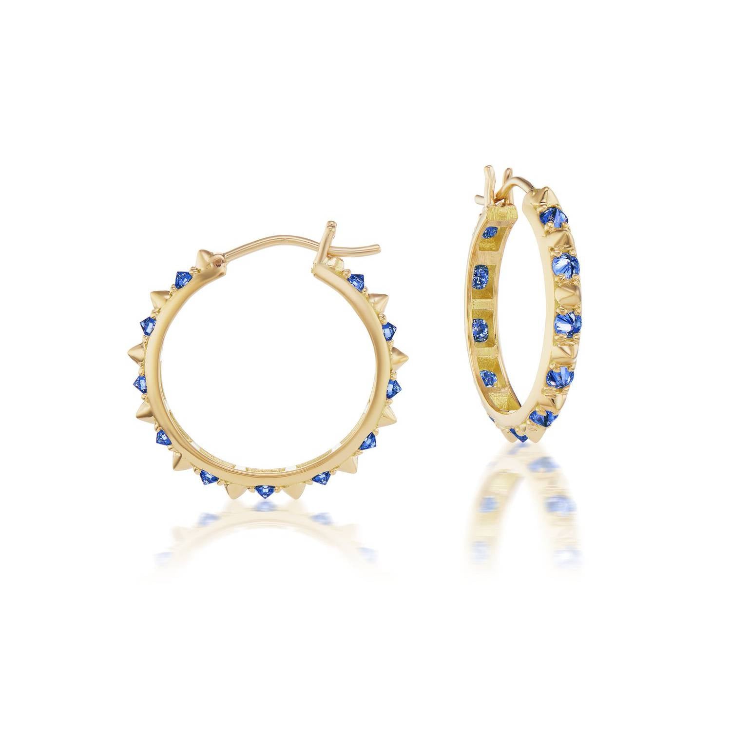 A side view of the opulent Large Valerie Blue Sapphire Hoops in blue and yellow, crafted with 18k yellow gold and adorned with inverted blue sapphires and gold spikes, they're a reinvented classic gold hoop earring.