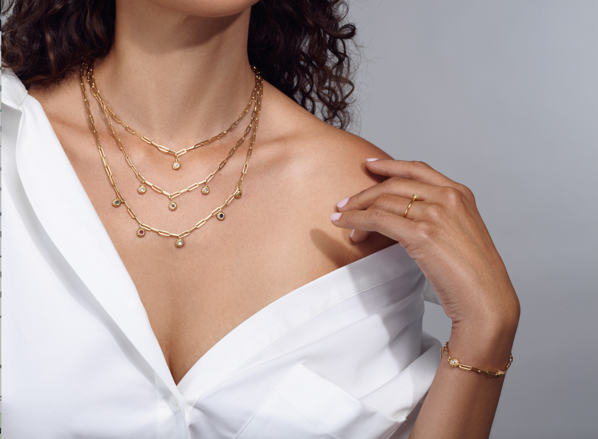 A model wearing various necklaces, rings, and bracelets from the ‘California Dreaming’ and ‘Tribe’ collections by Ana-Katarina Fine Jewelry. All pendants, rings, and bracelets are in 18k yellow gold in a sea-urchin-inspired design with soft gold beading - all with 18’ adjustable paperclip chains.