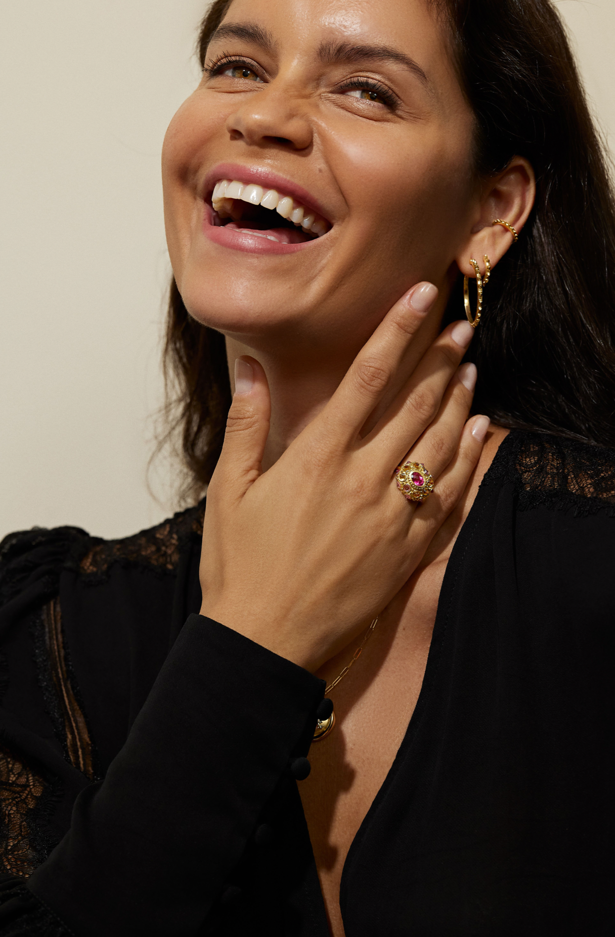 A model in a black blouse showcasing the stunning 18k yellow gold 'Adrina Loves a Hoop' mini gold hoop earrings from the AnaKatarina 'Attitude' Collection - as well as other fine gold jewelry rings, earrings, and ear cuffs designed by Ana-Katarina Fine JewelryThe gold spikes add a touch of rebellion to the elegant 18-karat gold edge. 