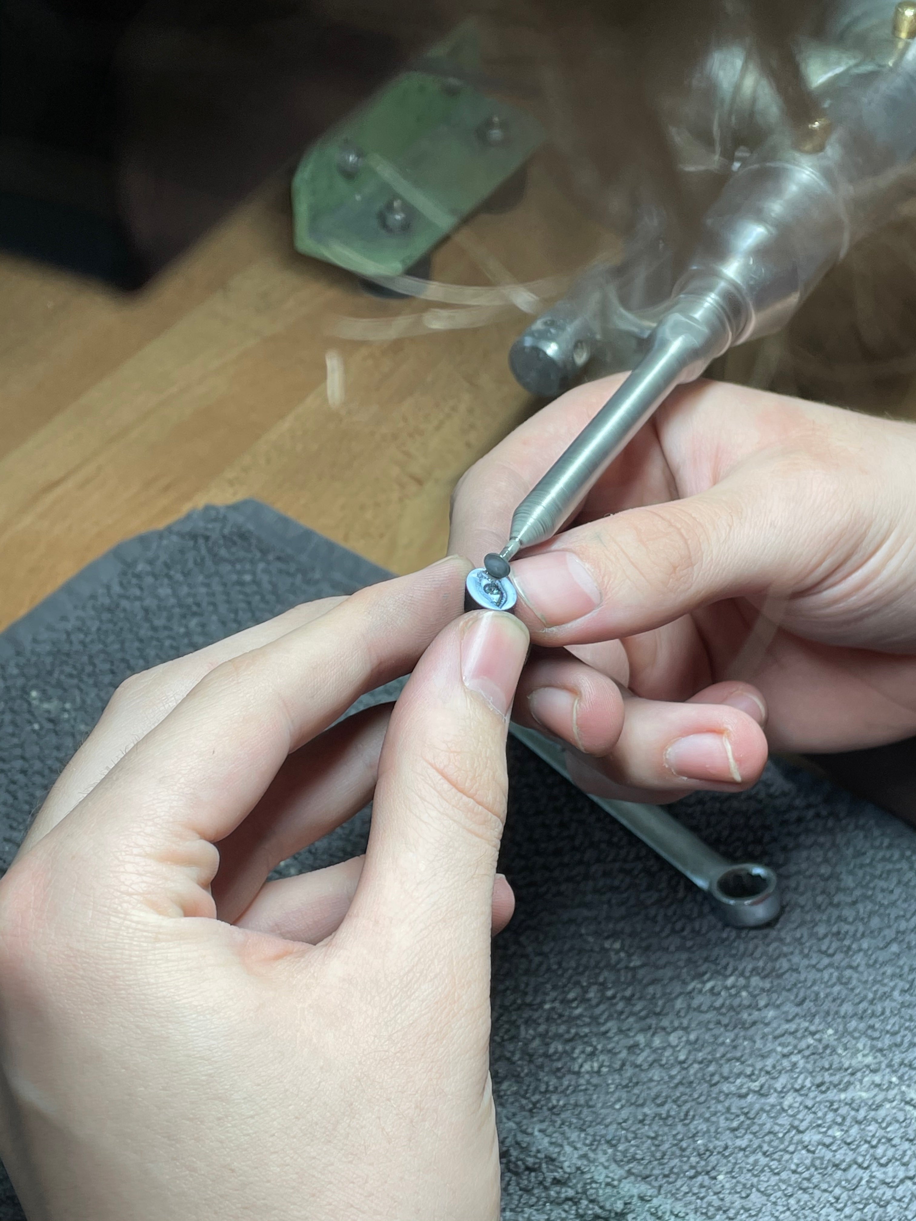 A closeup of a master crafter's hands carving an eye into blue agate in the creation of one of Ana-Katarina's ‘Eye Love’ Charm Bracelets. 